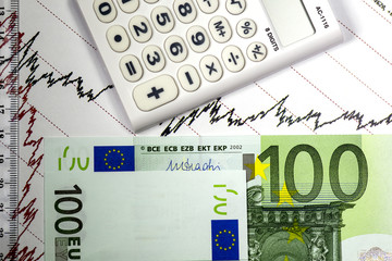 Stock market oil prices chart. Red and black lines on the diagram. Ruler and calculator on the graph.Hundred euro bills. Concept of oil stock market trading. Macro image.