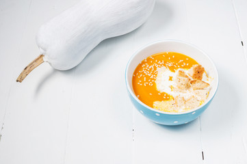 Pumpkin soup with fresh white pumpkins on a wood