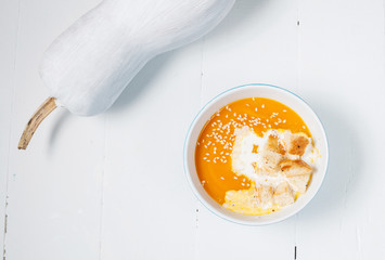 Pumpkin soup with fresh white pumpkins on a wood