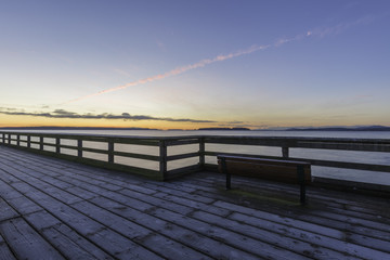 Fototapeta na wymiar Bench on a frosty dock with strong lines and a colorful sky.Vancouver Island Canada