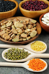 Dried various beans and lentils in wood bowls and spoons.