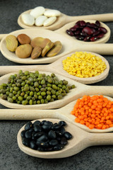 Dried various beans and lentils in wooden spoons.
