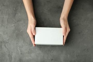 Female hands with white box on grey textured background