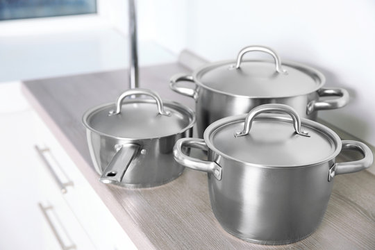 Kitchenware concept. Stainless saucepans on kitchen table