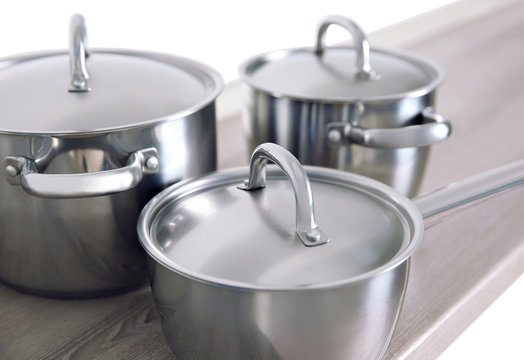 Kitchenware concept. Stainless saucepans on grey kitchen table, closeup