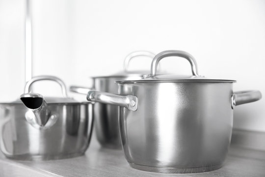 Kitchenware concept. Stainless saucepans on grey kitchen table, closeup
