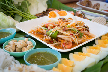kitchen table with spicy papaya salad, boiled egg and ingredient food, Thai national food, concept of hot asian food. Image focus top view.
