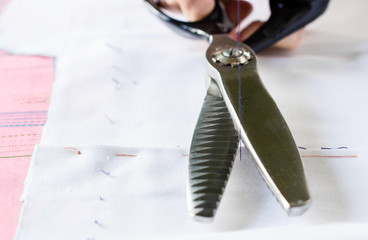 Naklejka premium Seamstress with scissors is cutting thread