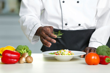 African American chef cooking tasty salad in kitchen, closeup
