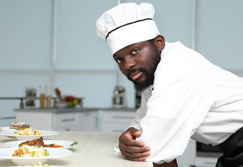 African American chef with tasty dishes in kitchen