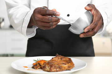 African American chef cooking tasty meat in kitchen, closeup