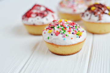 Cupcakes with white cream  and sprinkles on white background