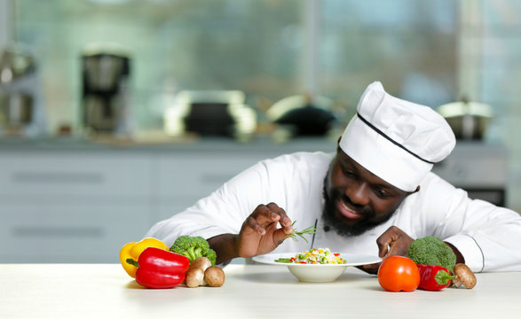 African American chef cooking tasty salad in kitchen