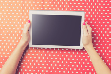 Woman holding white digital tablet over red dotted background