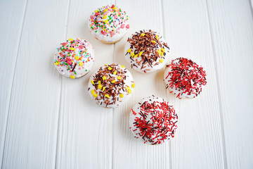 Cupcakes with white cream  and sprinkles on white background