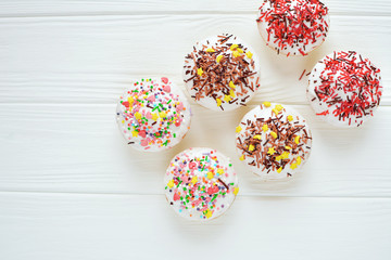 Obraz na płótnie Canvas Cupcakes with white cream and sprinkles on white background