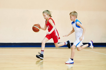 Naklejka premium Girl and boy athlete in uniform playing basketball