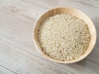 Coarse rice on the wooden plate and on wooden background