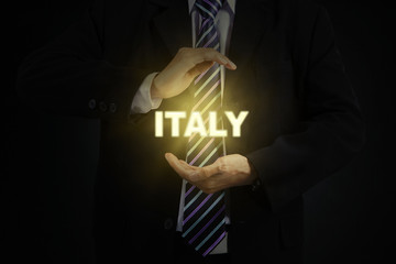 Businessman holding a bright word of Italy