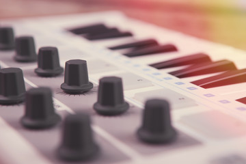 Close up of MIDI controller volume fader, knob and keys.