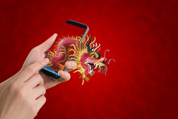 Fototapeta premium human hand hold smartphone, tablet, cell phone with big dragon.