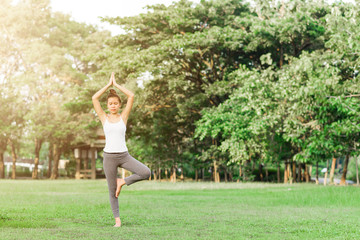 Girl do yoga pose at the park in the morning with sunlight.