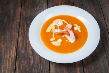 Pumpkin soup with shrimp on a wood