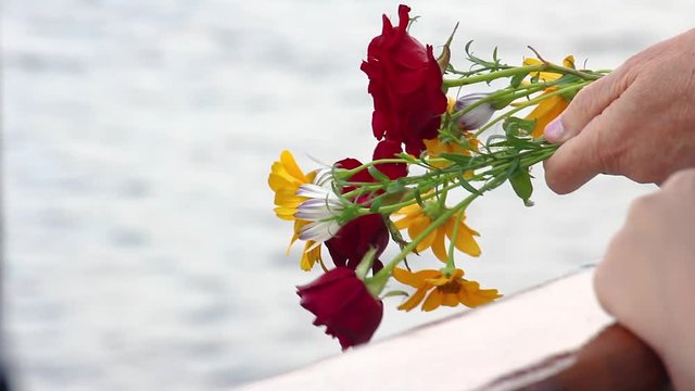 A bouquet of red and yellow flower in hands on a background of water. In memory of the fallen in the great Patriotic war and the battle of Stalingrad. Board the vessel on the Volga river, Volgograd