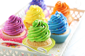 Tasty cupcakes in tray on a white wooden table