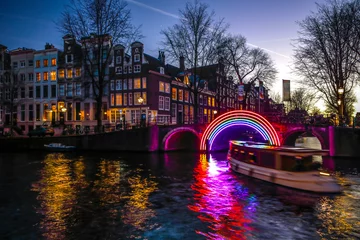 Foto op Canvas AMSTERDAM, NETHERLANDS - JANUARY 10, 2017: Cruise boats rush in night canals. Light installations on night canals of Amsterdam within Light Festival. January 10, 2017 in Amsterdam - Netherland. © Unique Vision