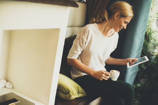 Young woman sitting in a cafe and holding a tablet in the hands