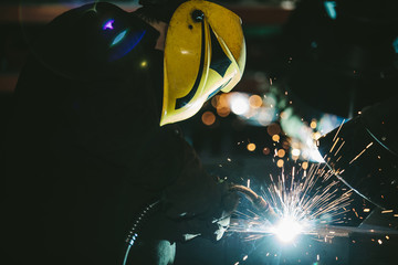 Worker at the factory in the helmet is of iron in the welding pr
