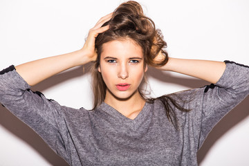Fototapeta premium Frustrated young woman covering ears by hands while standing against grey background