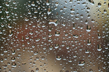 Rain drops on window with house and church in background 