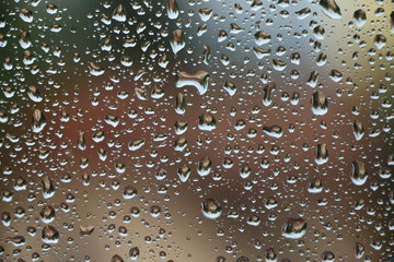 Rain drops on window with house and church in background 