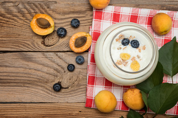 Yogurt with peach in a glass on  wooden background. Diet breakfast