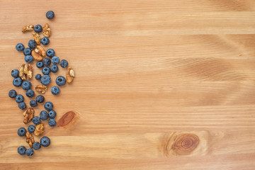 Blueberries and nuts on wooden background.