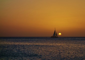 Sunset over a sailboat and the Caribbean Sea in Aruba