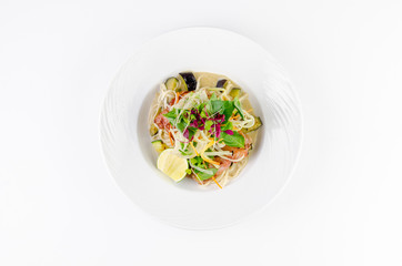 Fillet of sea bass with roasted eggplant and olives on a plate on a white background, top view