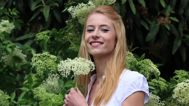 Young woman smelling on a elderberry flower in spring