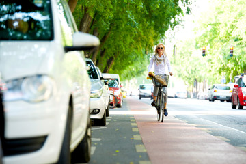 She goes everywhere by bike. Full length shot of a young woman in the street with a bicycle.