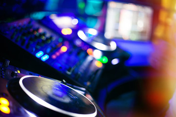 Fototapeta na wymiar DJ playing music at mixer closeup and mixes the track in the nig