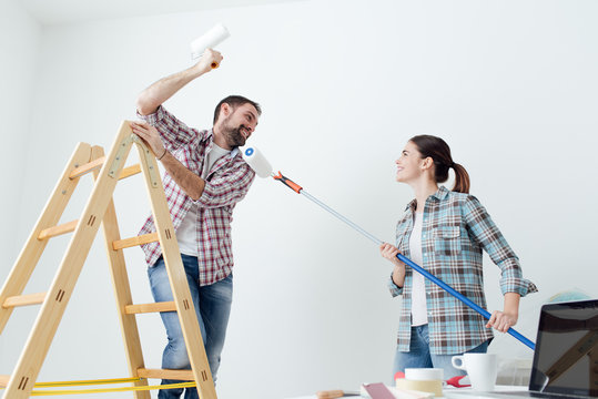 Playful couple painting walls