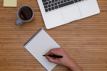 On top of the laptop, camera, coffee Cup hand writes in a notebook