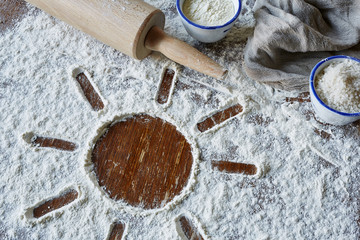 sun symbol in flour with utensils for baking