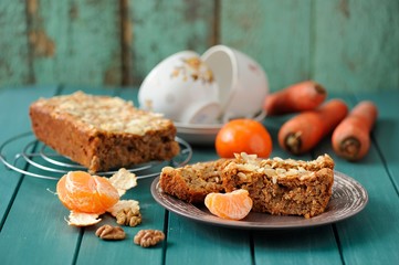 Homemade carrot cake with fresh carrots and clementines on turqu