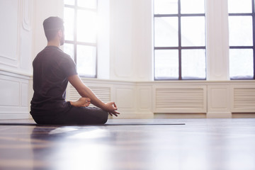 Young men do yoga indoors on black mat