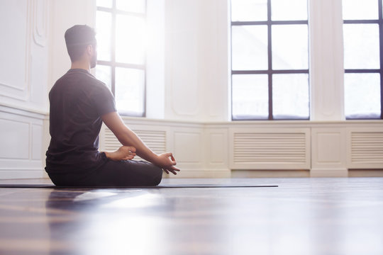 Young Men Do Yoga Indoors On Black Mat