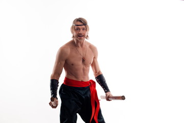 Actor Athlete man in trousers with naked torso practicing with wooden swords on a white background