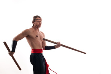 Actor Athlete man in trousers with naked torso practicing with wooden swords on a white background